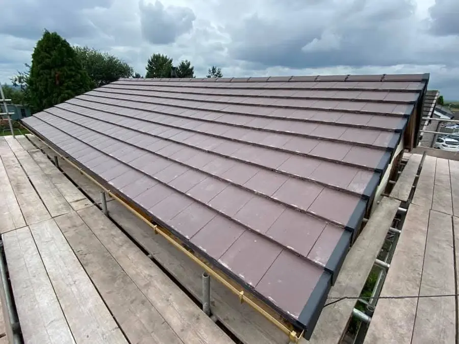 Brown flat tiles finished along a scaffolded roof