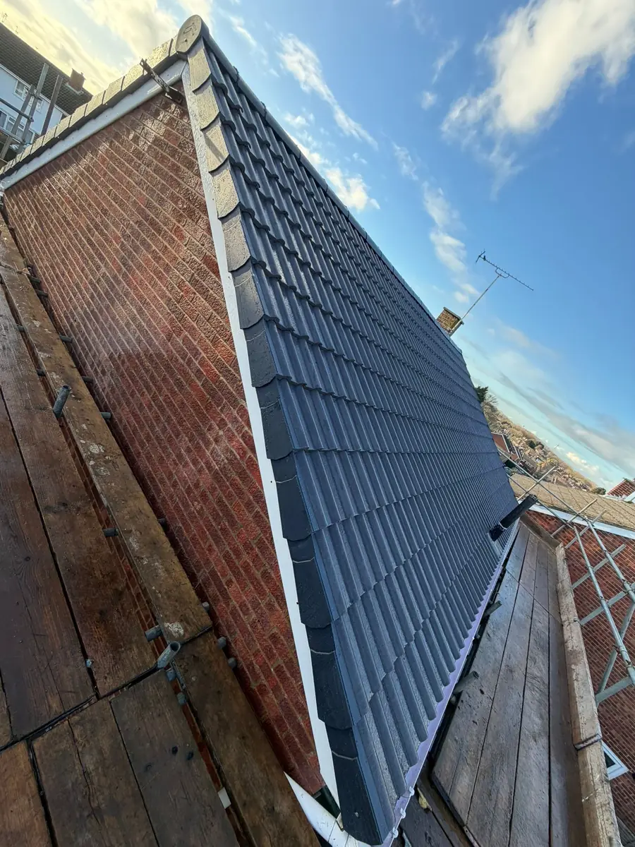 Dark slate-effect tiles on a gable, seen from the scaffold