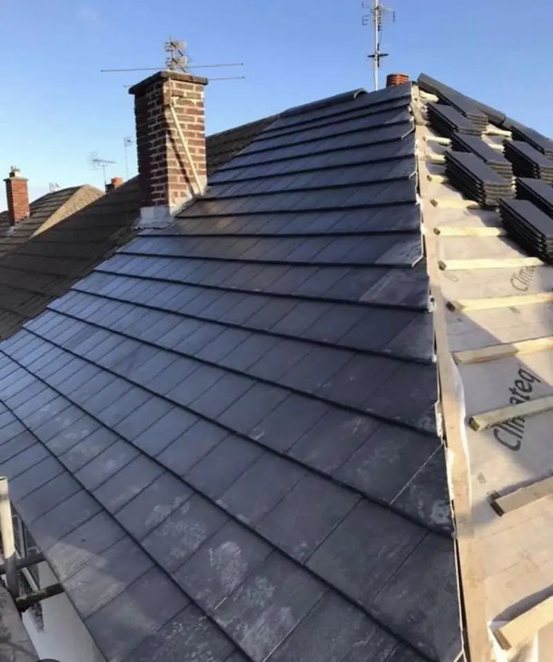 Dark tile hip roof with a dry hip and brick chimney