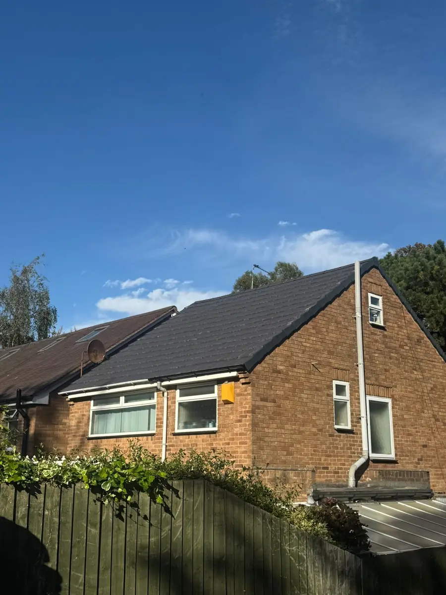 Finished dark tile roof on a detached house seen from the garden