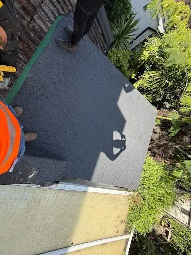 Roofer in hi-vis finishing a flat roof leak repair