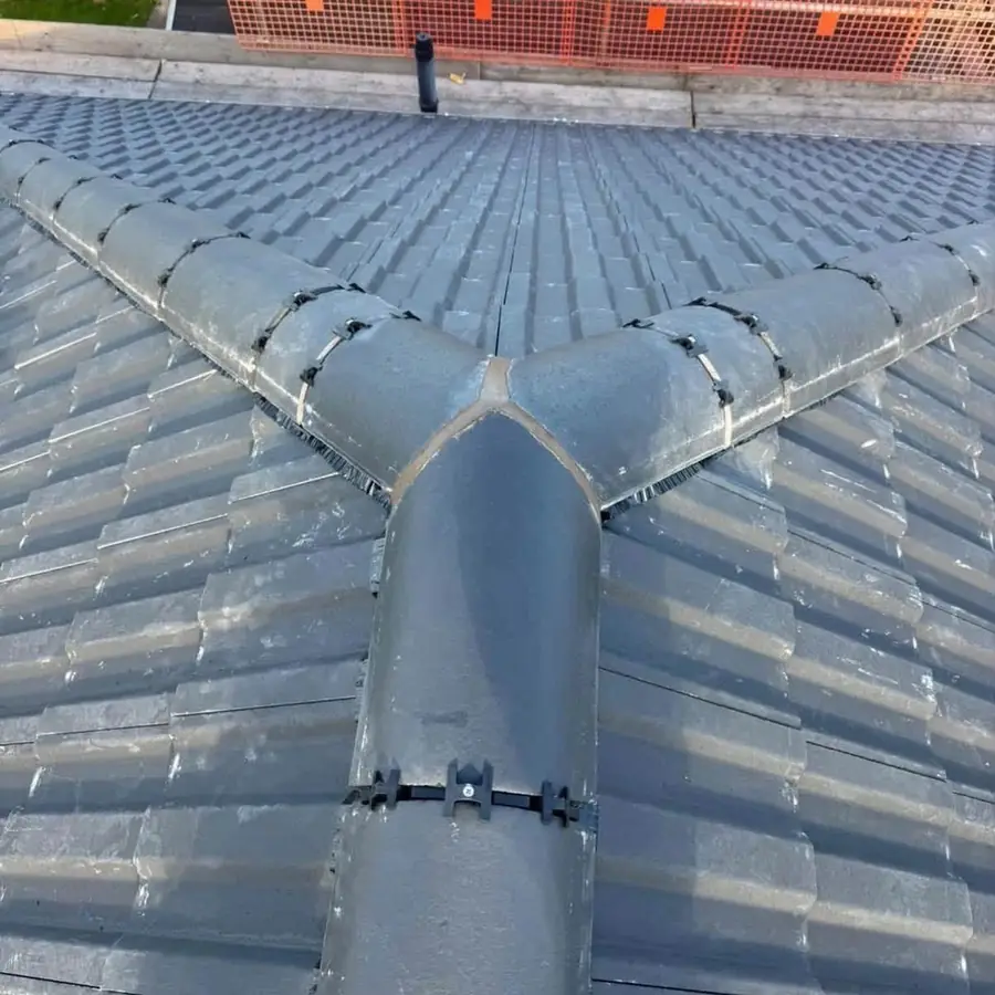 Grey dry hip and ridge junction on a new tile roof