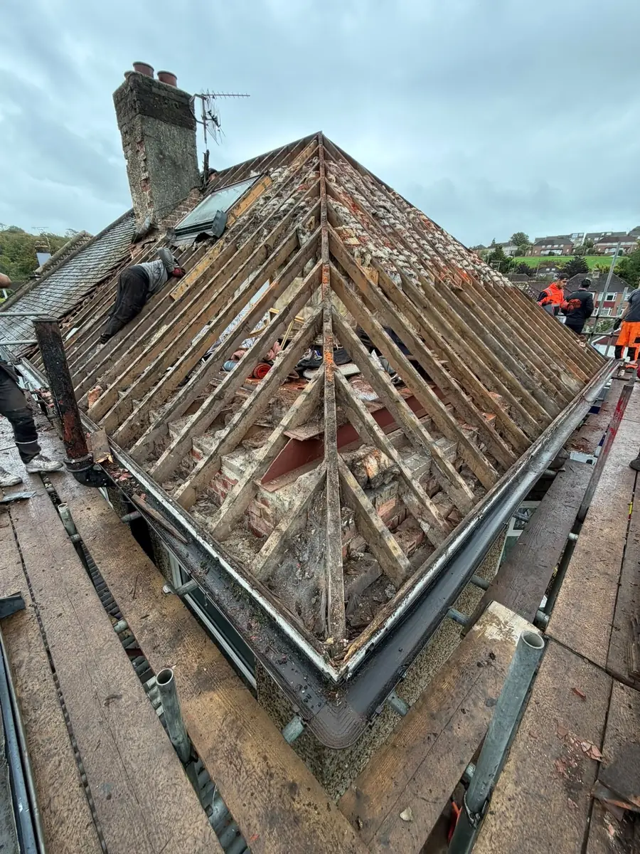 Hip roof stripped to the rafters beside a chimney