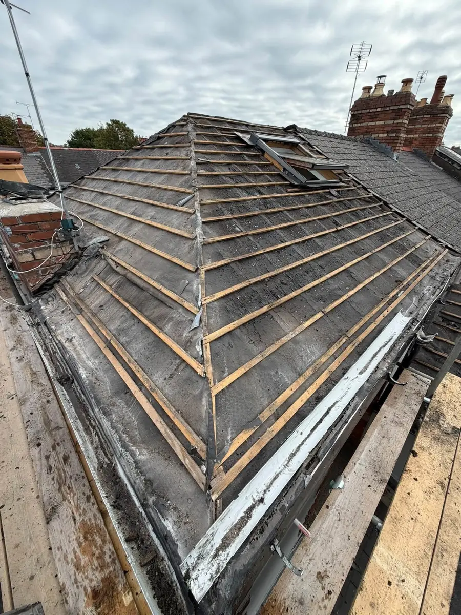Old battens and torn felt on a hip roof mid-strip