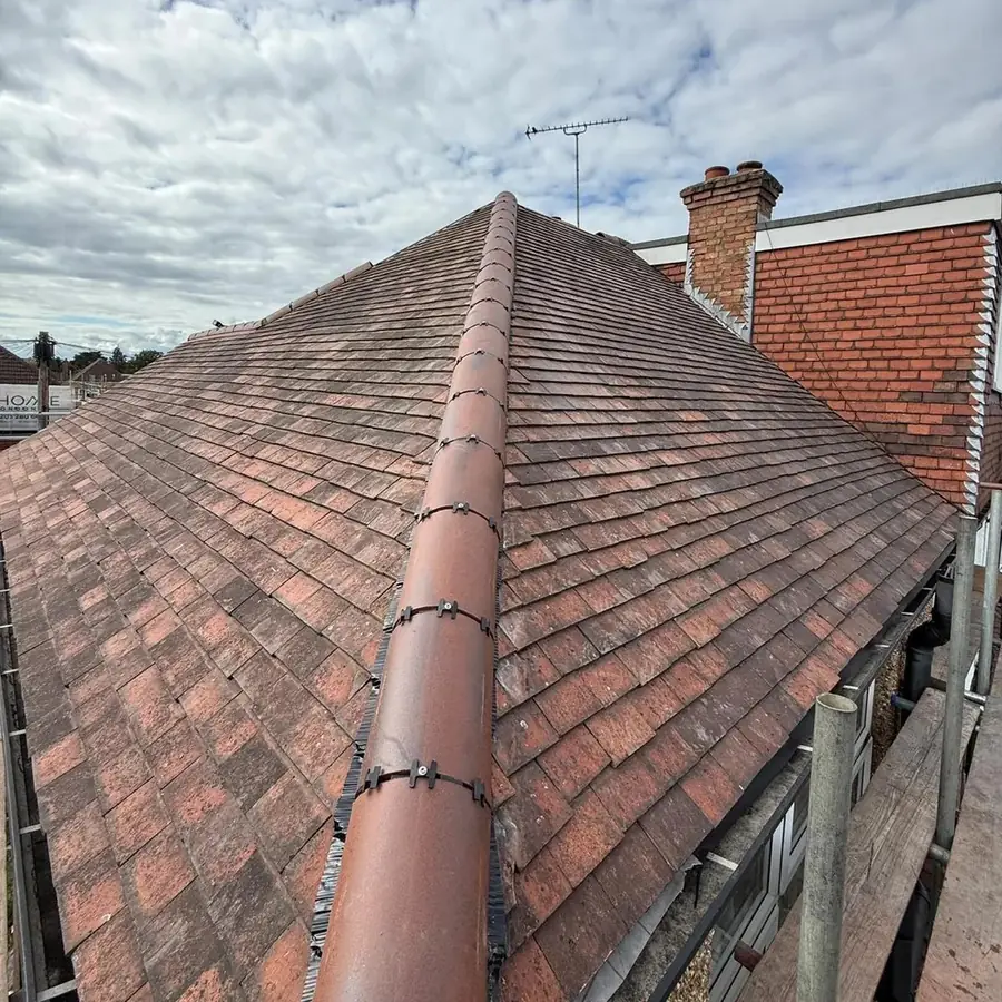 Plain tile hip roof finished beside a brick chimney
