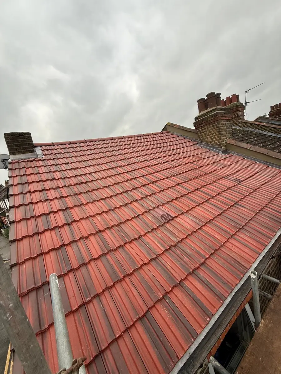 New red tile roof with a brick chimney stack behind
