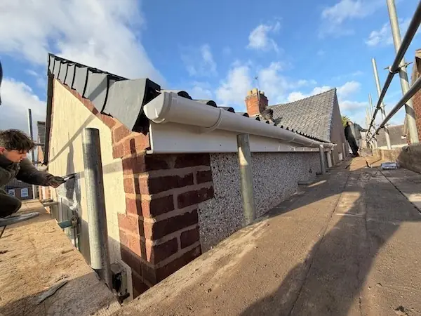WS & Sons roofer fitting new uPVC guttering down a side return