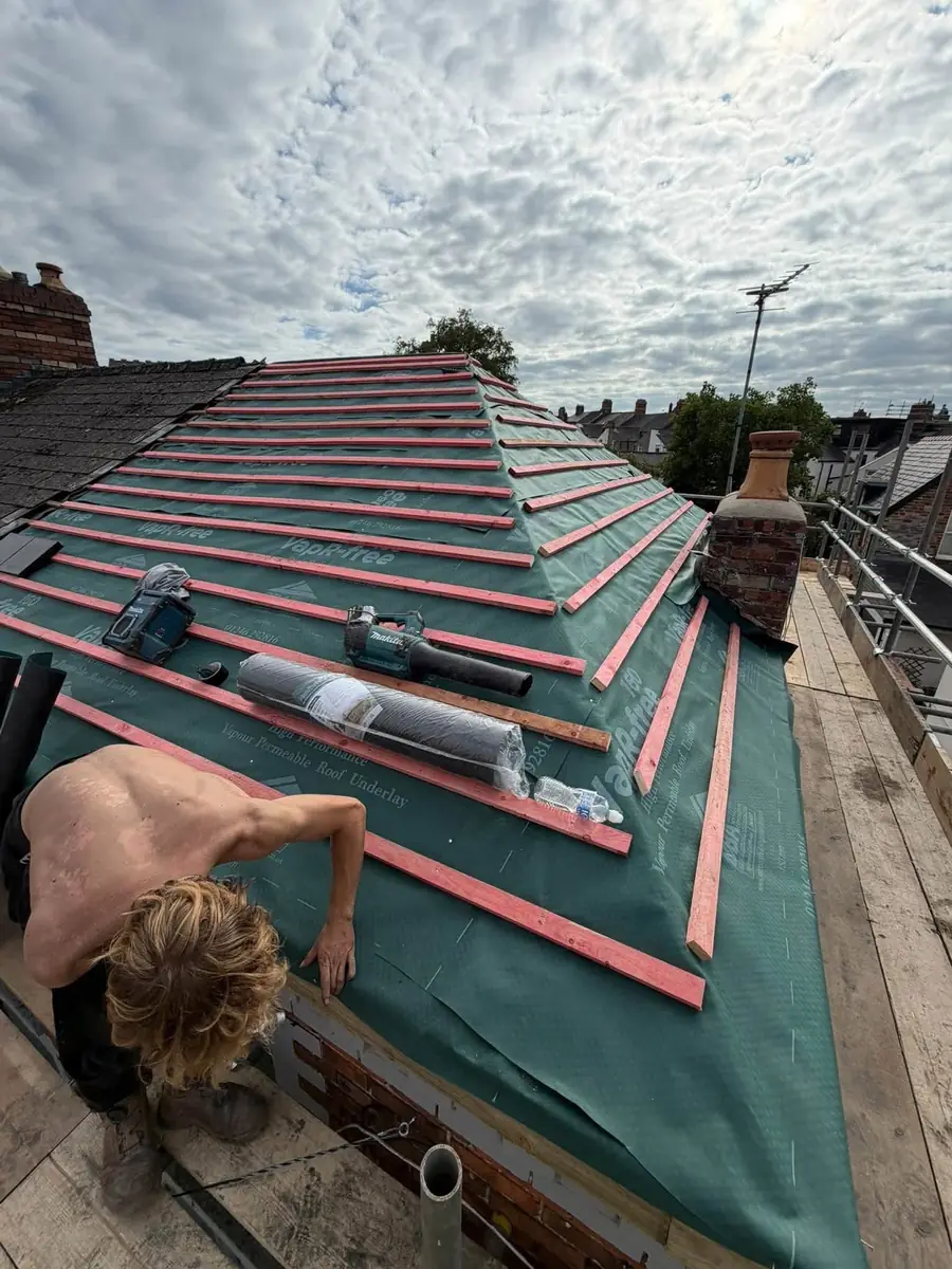 Roofer fixing new battens over red-lapped membrane