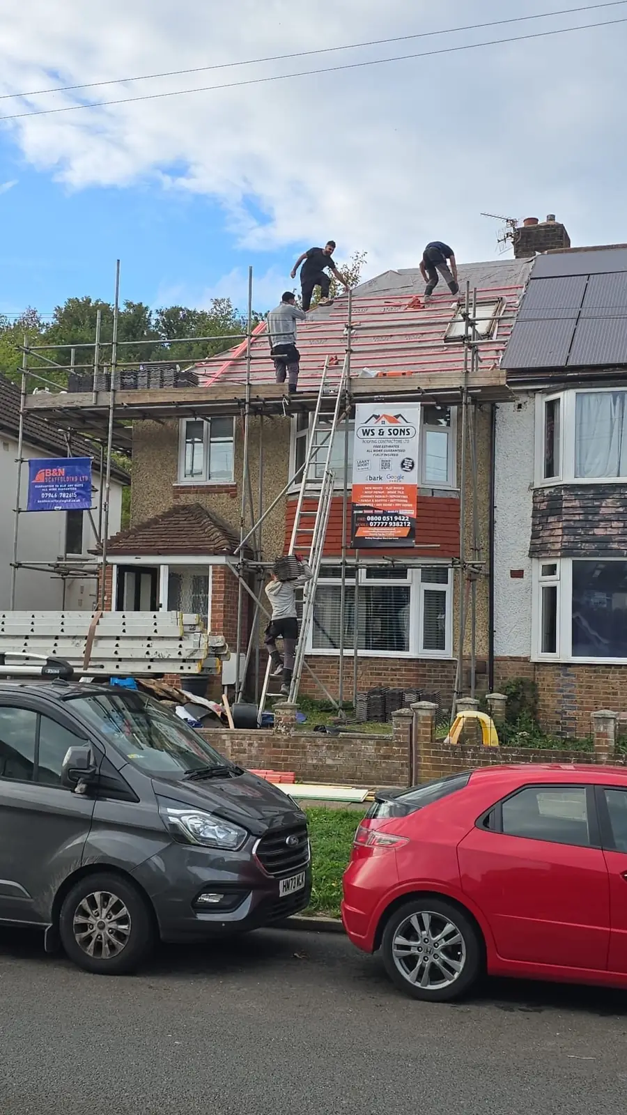 Scaffolded semi with the crew on the roof and the van outside