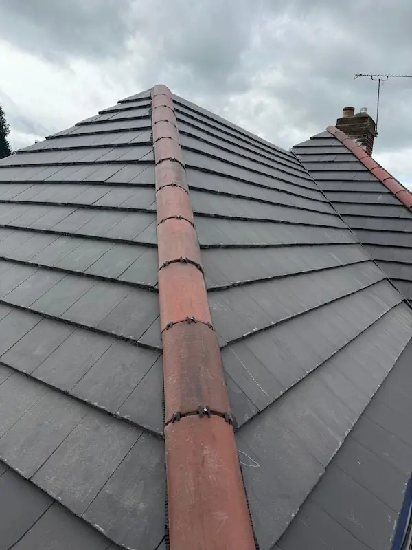 Slate hip roof finished with red clay ridge tiles